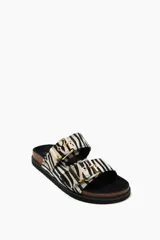 Sandalias planas con estampado de cebra, suela de corcho y hebillas doradas.