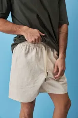 Short de gabardina color beige con calce relajado, cintura elástica con cordón ajustable y largo a mitad de muslo.