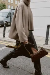Bolso de hombro con diseño alargado y acabado efecto cuero envejecido. Cuenta con cierre principal de cremallera, interior organizado con tres compartimentos y un bolsillo adicional con cierre. Incluye asa de hombro fija con detalles metálicos.