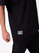 Remera de corte oversize color crema con estampado gráfico en la espalda que muestra un oso, un paisaje natural y el texto 'Stay close to the source'.