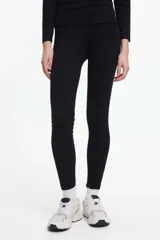 Calza larga negra de poliéster y elastano, ideal para mantener el calor en climas fríos.