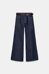 Jeans de tiro alto color azul oscuro, con cinco bolsillos, pernera ancha y nervio marcado en el delantero. Incluye un cinturón fino de cuero sintético marrón con textura de cocodrilo. Cierre frontal con cremallera y botón.