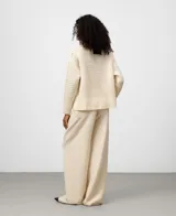 Jersey de lana cocida color crudo, con cuello perkins y manga larga. Presenta un punto calado con textura de rejilla en el cuerpo y punto canalé en puños y bajo.
