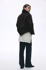 Campera oversized de doble faz con exterior de efecto gamuzado y forro interior de sherpa. Presenta cuello clásico, cierre frontal con botones, hombros caídos y bolsillos laterales insertados.