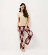 Pijama de dos piezas compuesto por una remera de manga corta en color beige con cuello redondo y un pantalón largo de corte recto con estampado de cuadros estilo argyle en tonos bordó y beige, con cintura elástica.