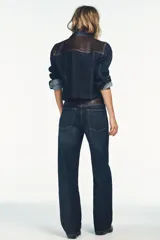 Jeans de tiro alto y pierna ancha con diseño de cinco bolsillos. Presenta una aplicación en la cintura de piel a contraste y cierre frontal con cremallera y botón metálico.