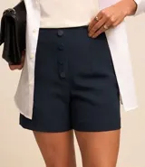 Short de sastrería negro, tiro alto, con cierre frontal de botones visibles.