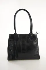 Cartera tote de cuero genuino color negro, con asas largas para el hombro. Presenta una franja central vertical con textura de cocodrilo y un adorno colgante de flecos (tassel) en el lateral.