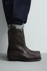 Bota estilo cowboy con acabado desgastado, tiradores laterales y horma cuadrada con tacón.