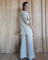 Pantalón de punto calado color crudo, de corte palazzo y cintura elástica.