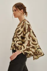 Camisa de lurex con estampado animal print en tonos dorados y marrones, con escote en V profundo y mangas amplias con volados. Incluye forro interior.
