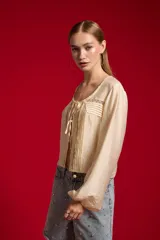 Blusa de lyocell color natural, holgada y de manga larga, con cuello redondo, detalles de encaje y lazo para anudar en el frente.