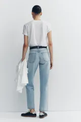 Jeans de tiro alto color negro con efecto lavado, corte mom fit, cinco bolsillos y cierre frontal con cremallera y botón metálico.