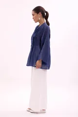 Camisa azul con cuello mao, abotonada al frente y mangas largas.