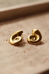 Caravanas de acero inoxidable bañadas en oro de 18K con diseño en forma de caracol.