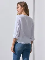 Blusa blanca de algodón marca Dash, con escote en V, abertura con botones, mangas 3/4 regulables con presilla y ruedo anudado.