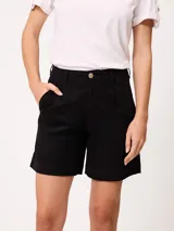Short negro de gabardina con pinzas delanteras, bolsillos laterales y cierre frontal con botón metálico.