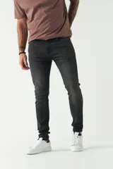 Jean skinny de hombre, color gris oscuro con efecto desgastado. Presenta cinco bolsillos, pasacinto y logo bordado.