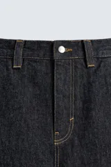 Pantalón chino de denim de algodón rígido, color índigo oscuro sin lavar. Corte baggy fit, tiro medio, con bolsillos frontales y traseros de plastrón. Presenta bordados a contraste en la cintura y en el bolsillo trasero.