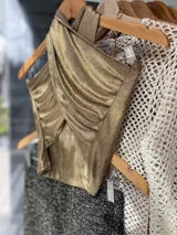 Top negro con diseño cruzado en el frente, estilo halter y con detalles de tachas doradas.