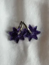 Aros tipo argolla dorada con dije colgante en forma de estrella de acrílico color rosa.