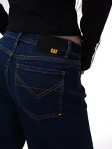 Pantalón de jean color azul oscuro con corte relajado, diseño de cinco bolsillos, cierre de cremallera y botón, y puños enrollados en la parte inferior de las piernas.
