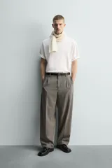 Pantalón de corte relajado con diseño de cuadros, confeccionado en tejido con lana. Presenta cintura con pliegues frontales, bolsillos laterales y bolsillos traseros de vivo, con cierre frontal de cremallera y gancho metálico oculto.