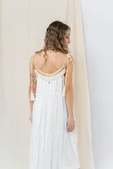 Vestido largo blanco de algodón con escote en V, breteles finos regulables con lazo y borlas, y detalle de tejido artesanal en el escote.