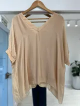 Blusa holgada de seda color crema, con escote en V y mangas cortas con vuelta.