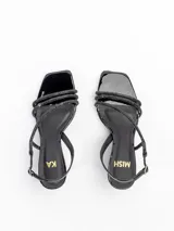 Sandalias de tacón medio modelo Loira, confeccionadas en cuero charol negro con tiras cruzadas cubiertas de strass. Tienen punta cuadrada, taco fino laqueado de 6,5 cm y tira ajustable al talón con hebilla.