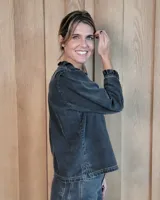 Camisa de manga larga con estampado de rayas verticales en tonos crudo y beige. Presenta cuello alto con volados, cierre frontal con botones dobles y puños con volados.