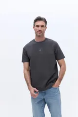 Remera de algodón con cuello redondo, manga corta y calce regular. Presenta un diseño minimalista con una pequeña estampa circular centrada en el pecho.