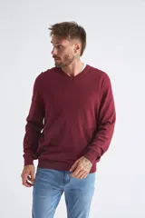 Sweater de tejido de punto color beige, con escote en V, mangas largas y puños y dobladillo acanalados. Presenta un pequeño logo bordado en el pecho.