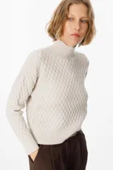 Sweater color crudo con cuello alto y diseño de tejido panal.