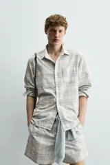 Camisa regular fit confeccionada en tejido de algodón con diseño de cuadros en tonos celestes y beige, cuello con botones, manga larga con puño abotonado y bolsillo de parche en el pecho.
