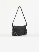 Mini cartera bandolera de cuero vacuno flor color negro con interior al tono. La correa regulable combina cuero y pelo, y lleva hebillas metálicas personalizadas.