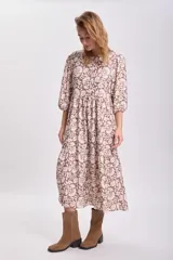 Vestido largo de corte holgado con diseño de paneles escalonados, estampado floral en tonos marrón y beige, cuello redondo y mangas tres cuartos abullonadas.