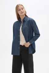 Sobrecamisa de jean en tono celeste claro, con cuello clásico, cierre frontal con botones metálicos y bolsillos frontales tipo parche.
