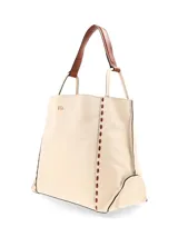 Cartera tipo shopper amplia de cuero graneado color crema, de moldería clásica y formato rectangular. Presenta pespuntes decorativos a contratono en los laterales y asas al hombro con correas de cuero. Incluye detalle de logo metálico frontal.