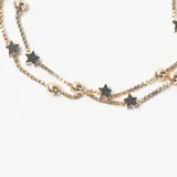 Pulsera de doble cadena tipo veneciana en color dorado, decorada con pequeñas esferas lisas y dijes en forma de estrella distribuidos a lo largo de ambas cadenas.