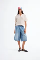 Remera color crudo de tejido calado con cuello polo y mangas cortas.