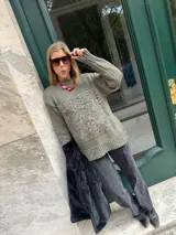 Buzo de tejido de punto grueso color marrón con diseño geométrico y floral estampado en color rojo. Presenta cuello redondo, mangas largas y puños y ruedo acanalados.