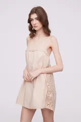 Vestido corto color marfil con breteles finos, escote recto y detalle de puntilla en los laterales y ruedo.