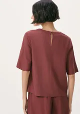 Blusa de manga corta con cuello redondo, confeccionada en tejido de lino con textura natural, de corte recto y ajuste cómodo.
