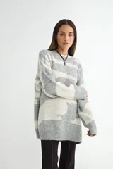 Buzo de tejido de punto con diseño estampado de manchas abstractas en tonos gris y blanco, de corte holgado y cuello redondo.
