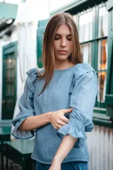 Blusa color rosa pálido de algodón con mangas cortas abullonadas y volados en el escote.