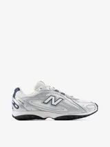 Championes New Balance modelo U204LPC, de estilo inspirados en el running de los años 2000, con capellada de malla blanca y superposiciones metalizadas plateadas con detalles en azul marino.