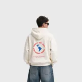 Hoodie de color blanco con capucha, corte holgado y diseño gráfico estampado en la espalda que incluye un mapa del mundo en azul y texto en rojo.
