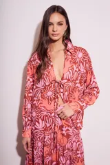 Blusa de poliéster con estampado de flores y animales en tonos rosa y marrón. Tiene cuello camisero, mangas largas y cierre frontal con lazo.
