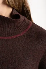 Sweater de punto con cuello alto, diseño oversize y mangas largas. Presenta un contraste de color en el cuello y una franja vertical en las mangas en tono beige.
